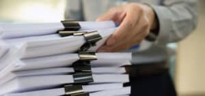 Plano cerrado de persona apilando documentos como ejemplo de 8 procesos de gestión documental eficientes con Legarchivo