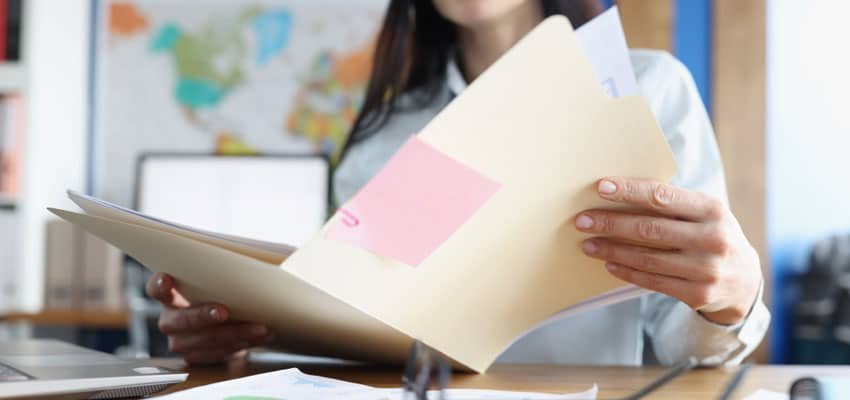 Mujer con documentos disfrutando de las ventajas de un sistema de gestión documental realizada por expertos de Legarchivo