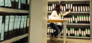 Mujer trabajando en un cuarto de archivo mostrando las ventajas de un sistema de gestión documental implementado por expertos de Legarchivo